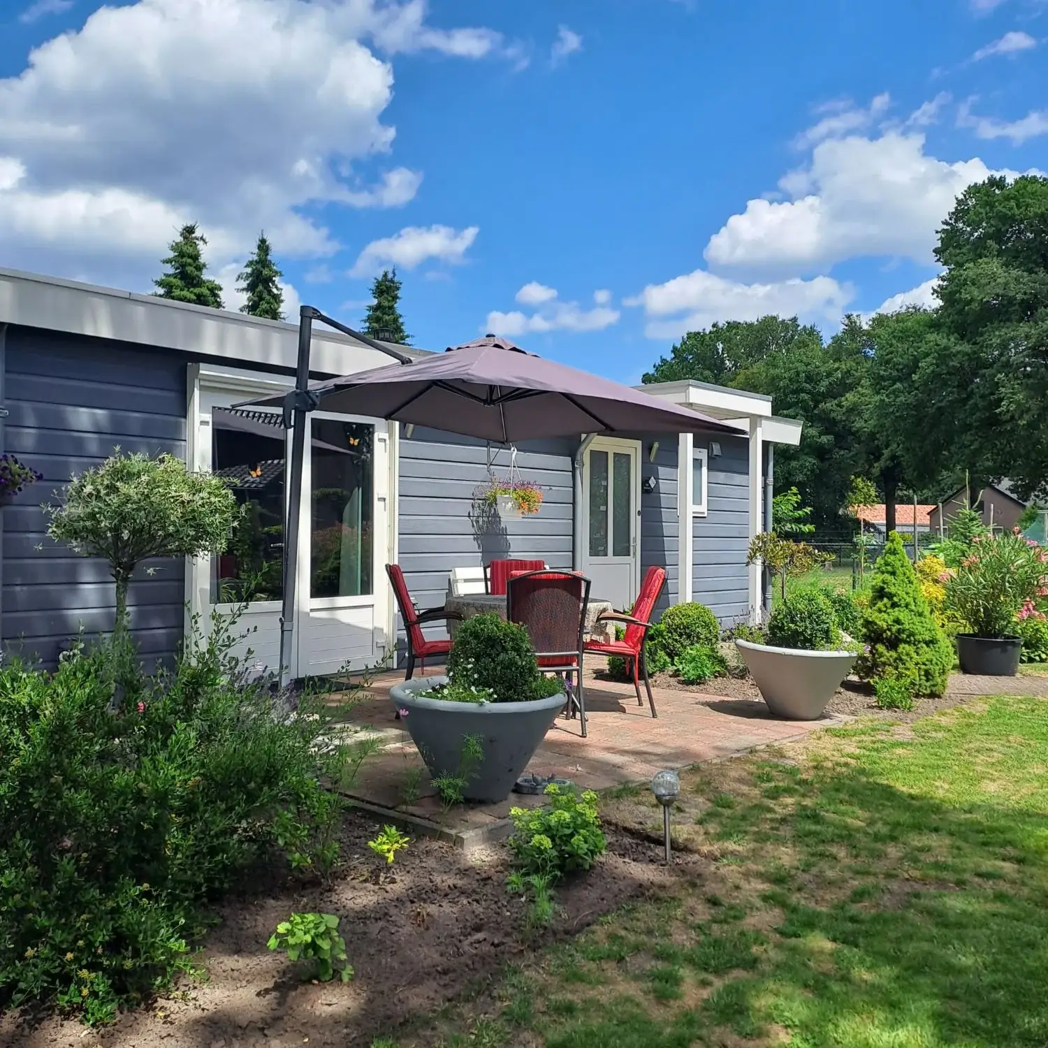 Terras met tuinset voor het donkerblauwe chalet van B&B Sterrenhemel